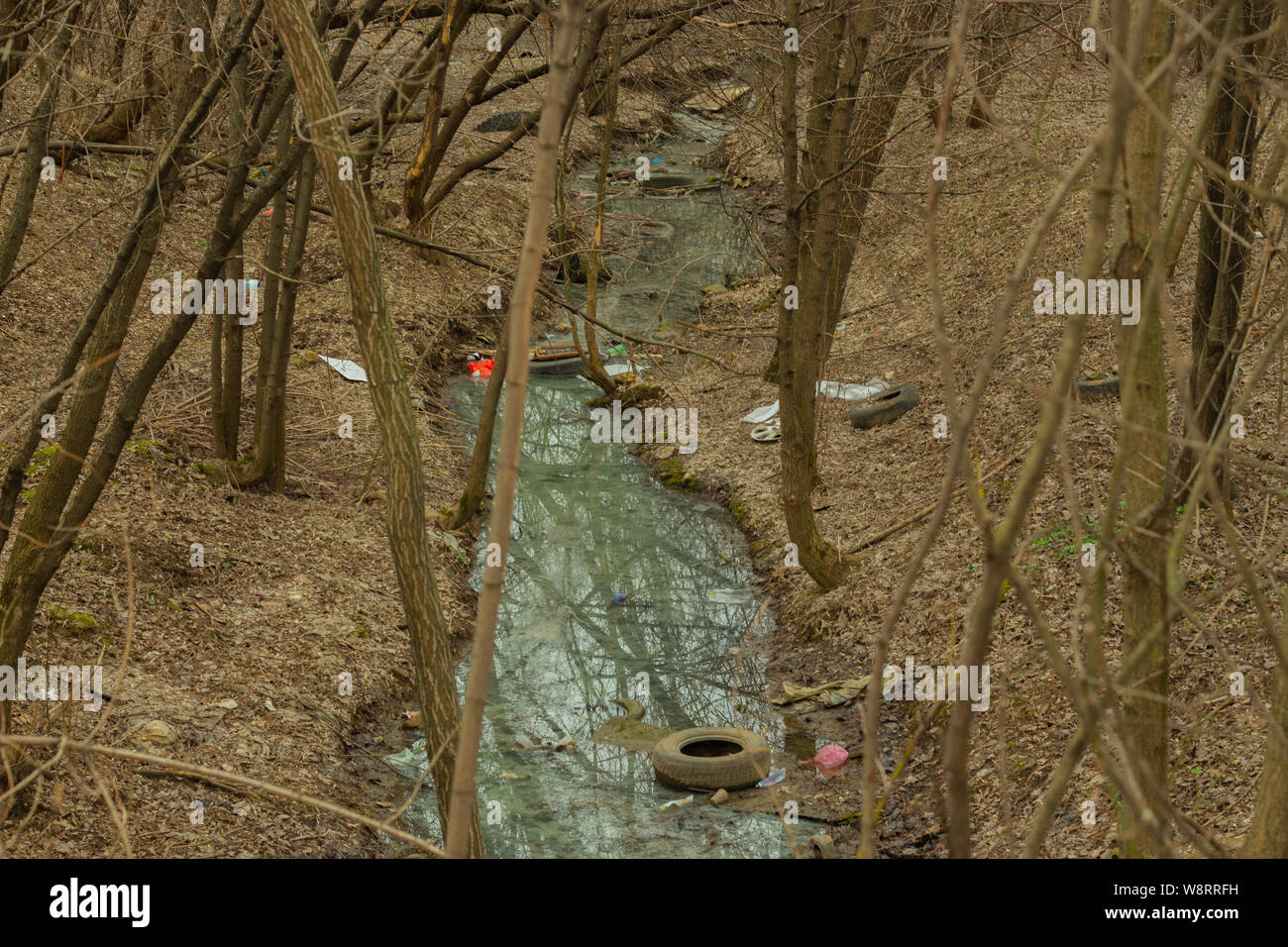 Forêt de printemps rivière flux des déchets Déchets de pneus en plastique bouteilles en verre une fois la neige fondue. Les questions environnementales, la pollution de la planète, la collecte des déchets Banque D'Images