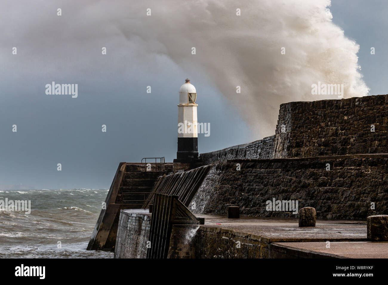 Ocean vagues se brisant sur un mur du port à côté d'un phare sur un jour de tempête, Porthcawl (Pays de Galles, Royaume-Uni) Banque D'Images