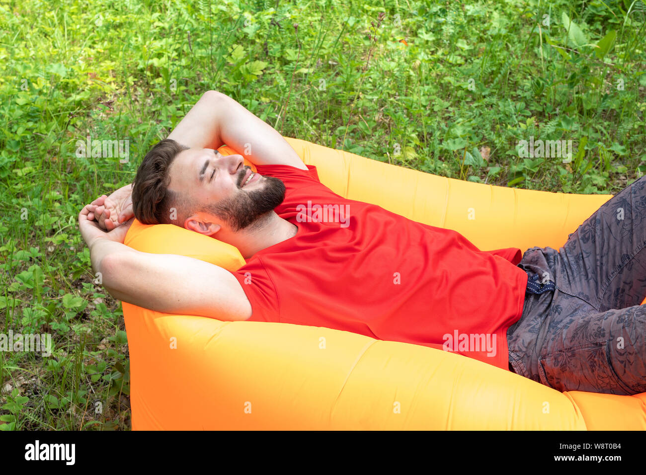 Un jeune homme se trouve sur un matelas d'air ou un canapé avec ses yeux fermés, de sourires, de rêves et de silences. Passe-temps agréable, de détente dans la nature Banque D'Images