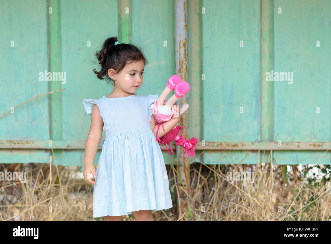 Adorable petite fille en robe couleur menthe holding doll, debout, en  attente d'un bus sur une station de bus, le retour à l'école préscolaire ou  concept Photo Stock - Alamy