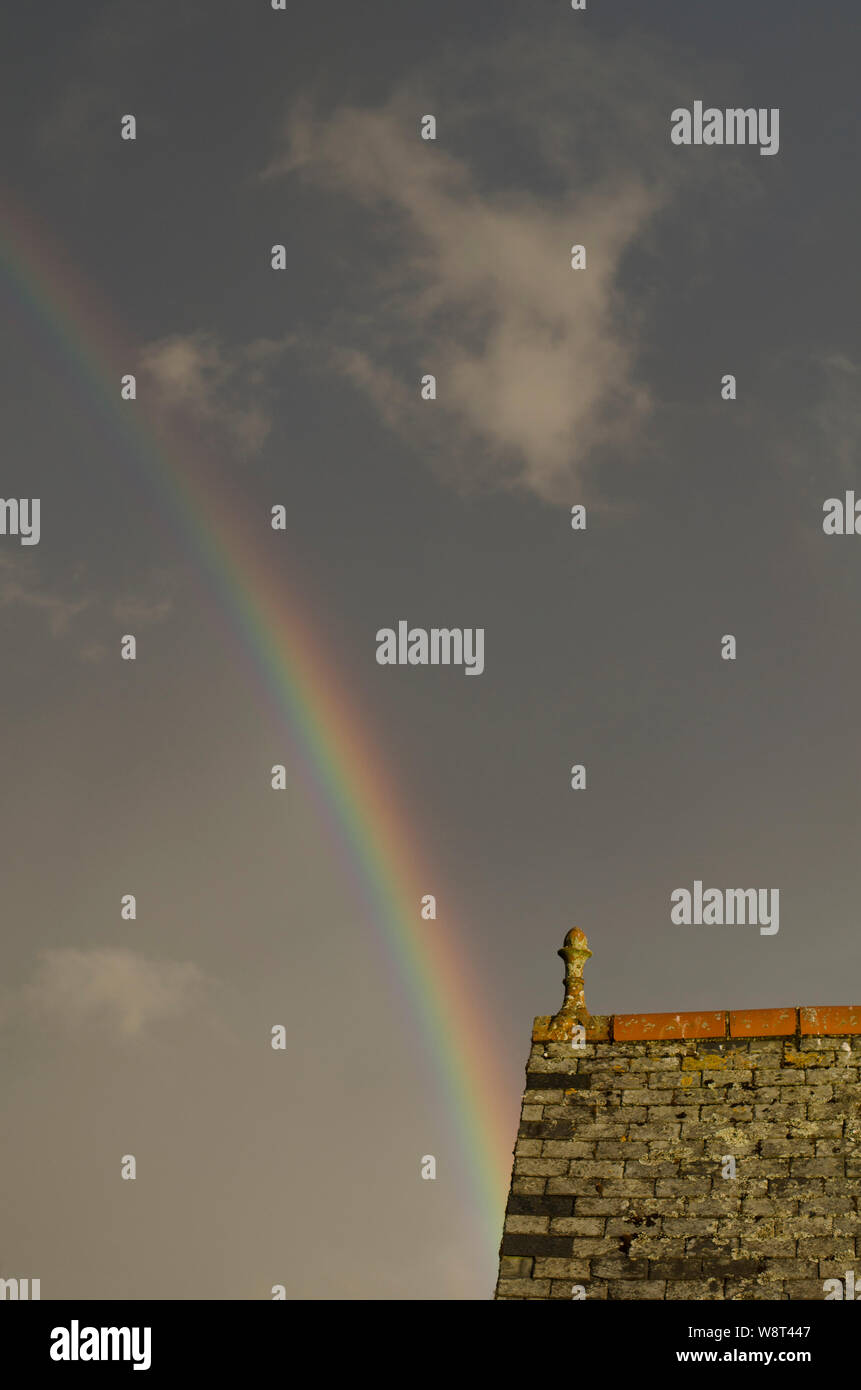 Partie d'un arc-en-ciel avec le bord du toit Banque D'Images