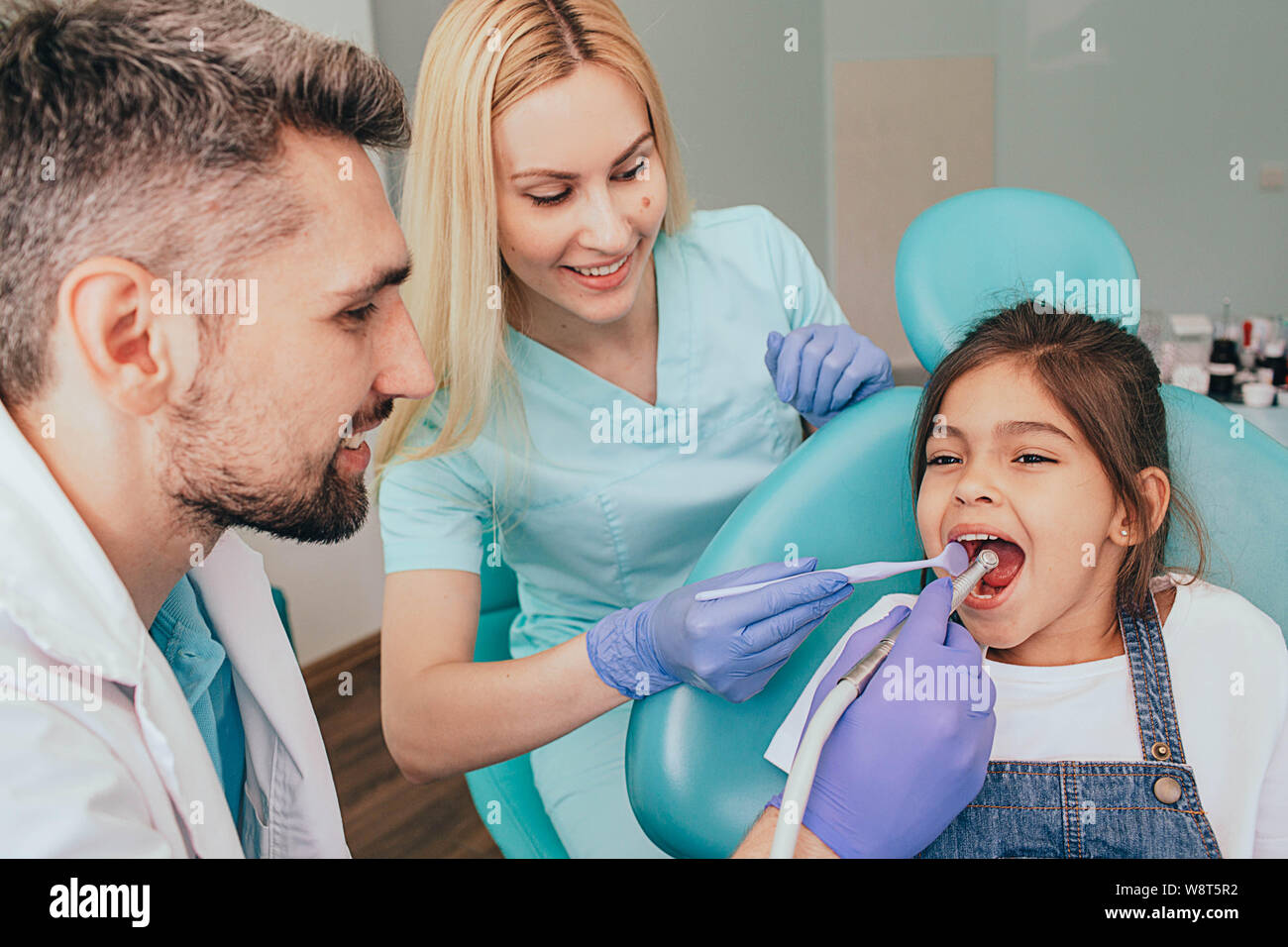 Dentiste et son assistant sont traiter les dents d'une petite fille. La Dentisterie Pédiatrique Banque D'Images