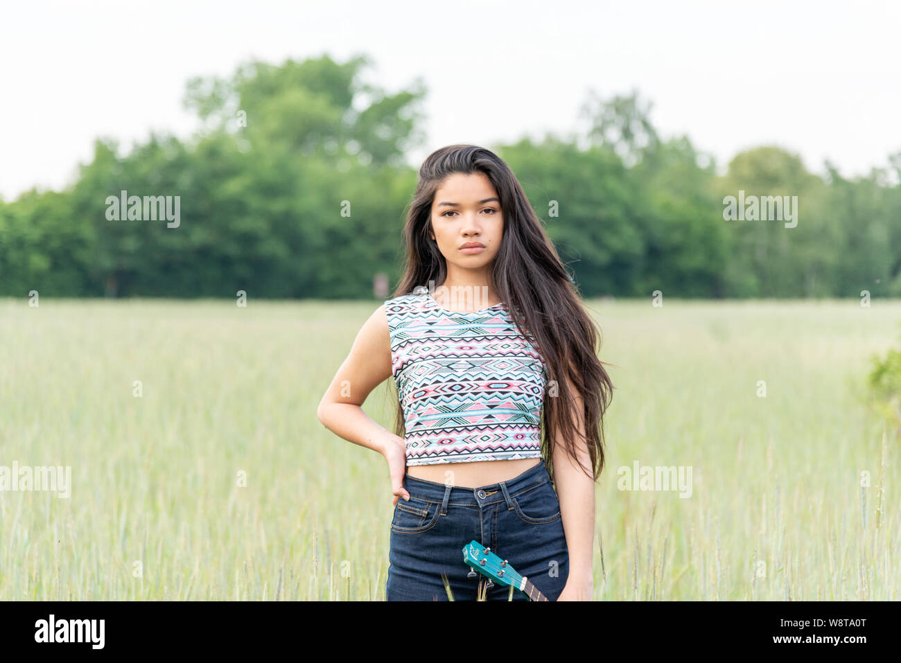 Belle jeune femme asiatique avec de très longs cheveux et un ukulélé en plein air Banque D'Images