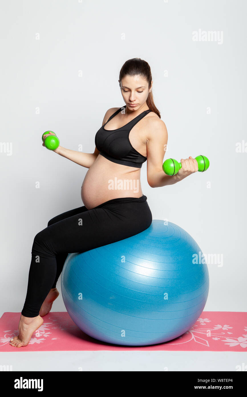 Young pregnant woman doing gymnastics avec fitball et haltères. Banque D'Images