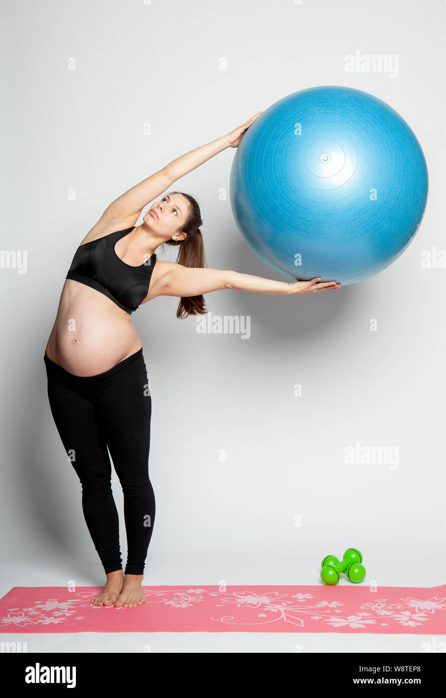 Young pregnant woman doing gymnastics avec fitball et haltères. Banque D'Images