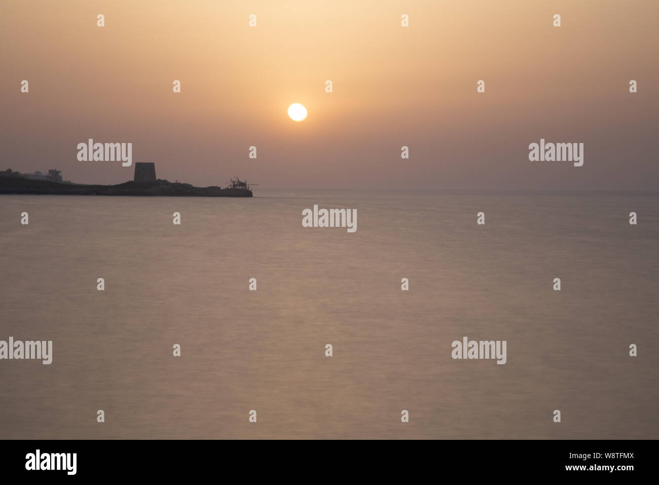 Coucher du soleil d'été au large de la côte de la péninsule du Gargano, sur le continent est une ancienne tour de défense et une maison appelée pêche trabucchi, Italie Banque D'Images