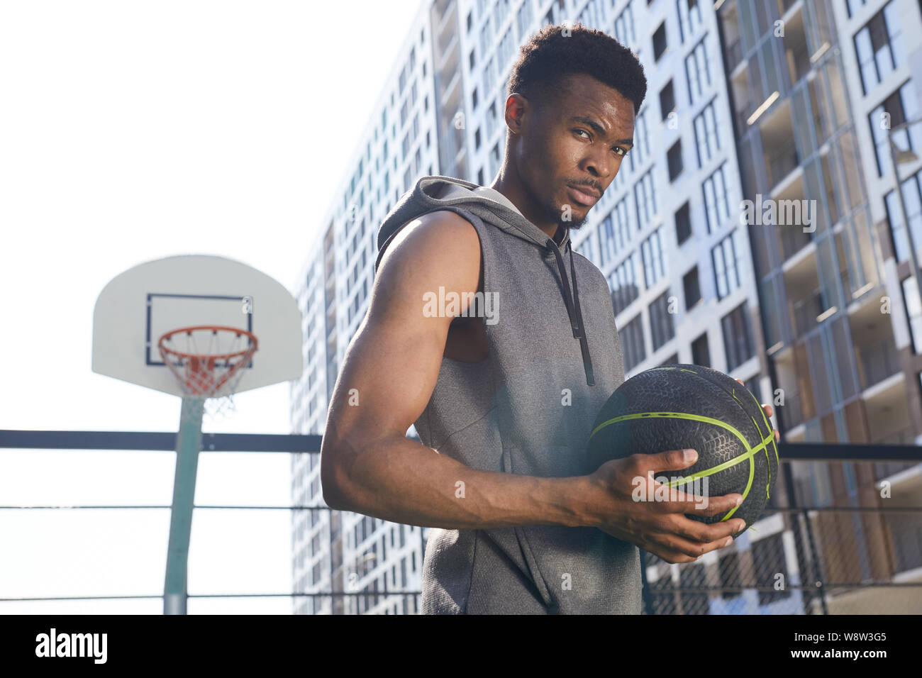 Taille portrait of handsome man holding afro-américain de basket-ball ball and looking at camera avec confiance, copy space Banque D'Images
