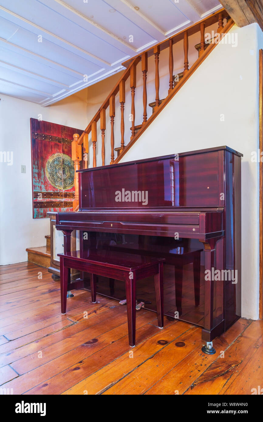 Piano droit bordeaux à côté de l'escalier en bois de pin menant à l'étage à  l'intérieur d'une ancienne maison en pierre de 1820 style cottage Photo  Stock - Alamy