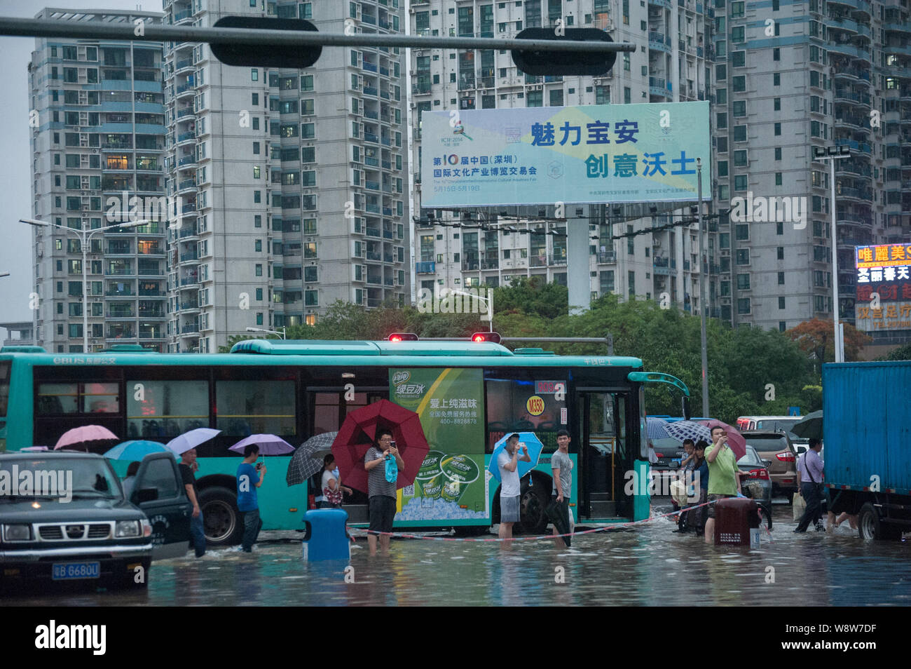 Les piétons passent devant les véhicules bloqués par les inondations causées par des pluies torrentielles sur une route dans la ville de Shenzhen, province de Guangdong, en Chine du sud 11 mai 2014. À Banque D'Images