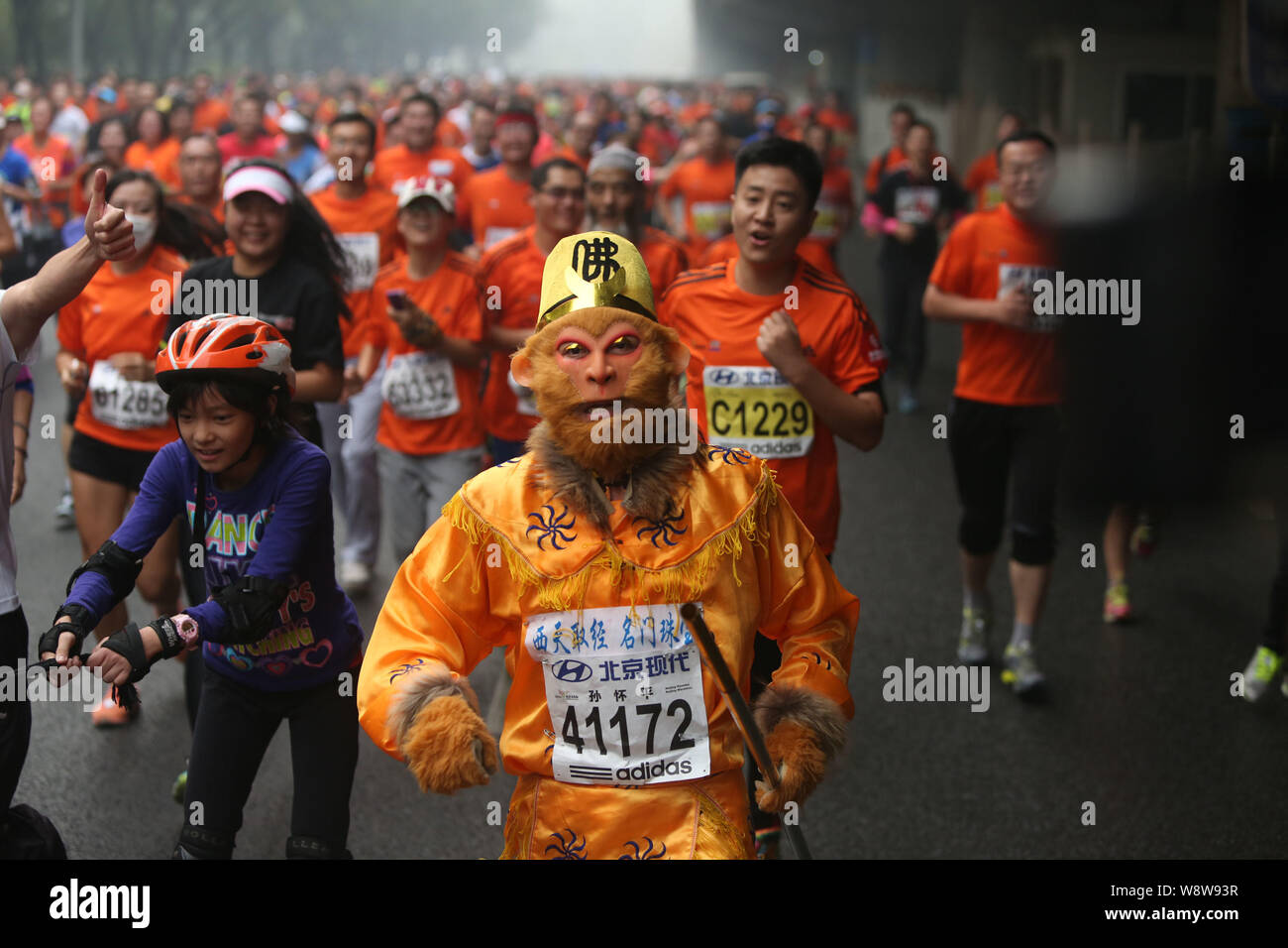 Un participant chinois habillé comme le Roi Singe fonctionne avec d'autres participants au cours de la Beijing 2014 Marathon International de Pékin dans le smog lourd Banque D'Images