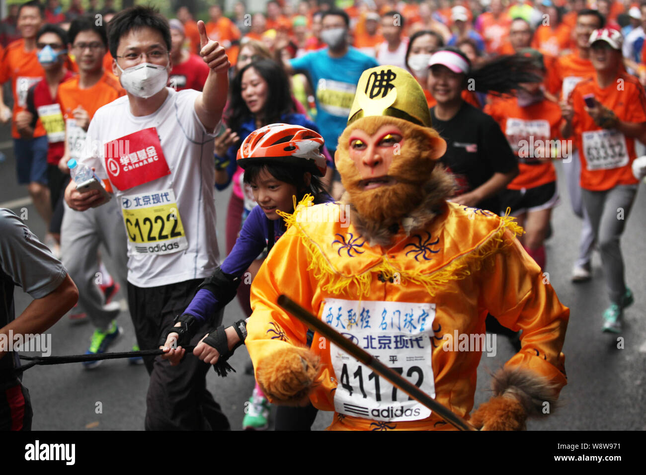 Un participant chinois habillé comme le Roi Singe fonctionne avec d'autres participants au cours de la Beijing 2014 Marathon International de Pékin dans le smog lourd Banque D'Images