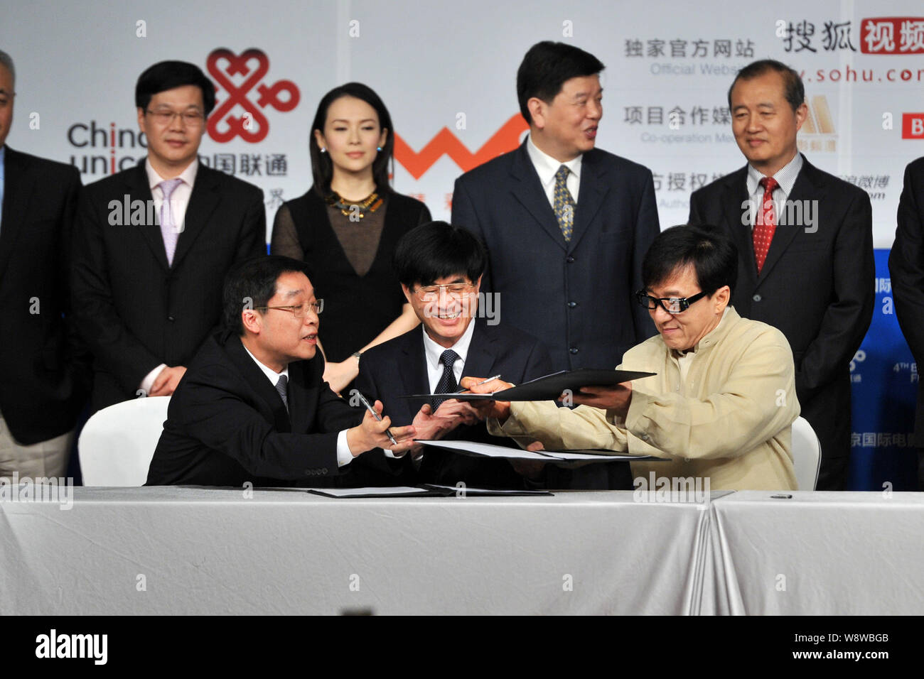 L'acteur de Hong Kong Jackie Chan, avant droit, d'échanges conclus avec des représentants de groupes d'investissement de film au cours d'une cérémonie de prise de vue pour son nouveau m Banque D'Images