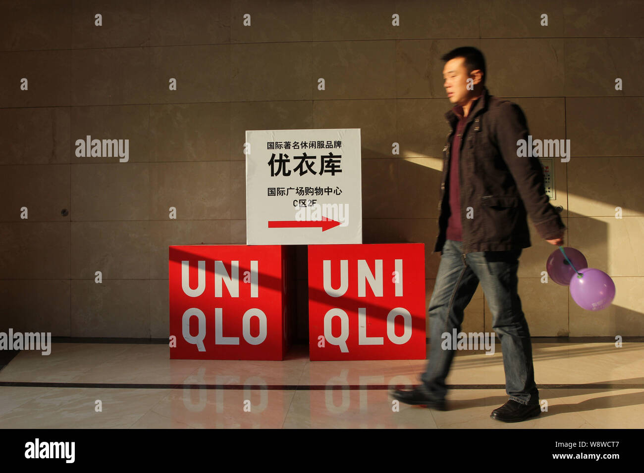 FILE--un piéton passe devant une publicité pour Uniqlo à Wuhan, province de  Hubei, Chine centrale 1er janvier 2014. Fast Retailing co. Chef E Photo  Stock - Alamy