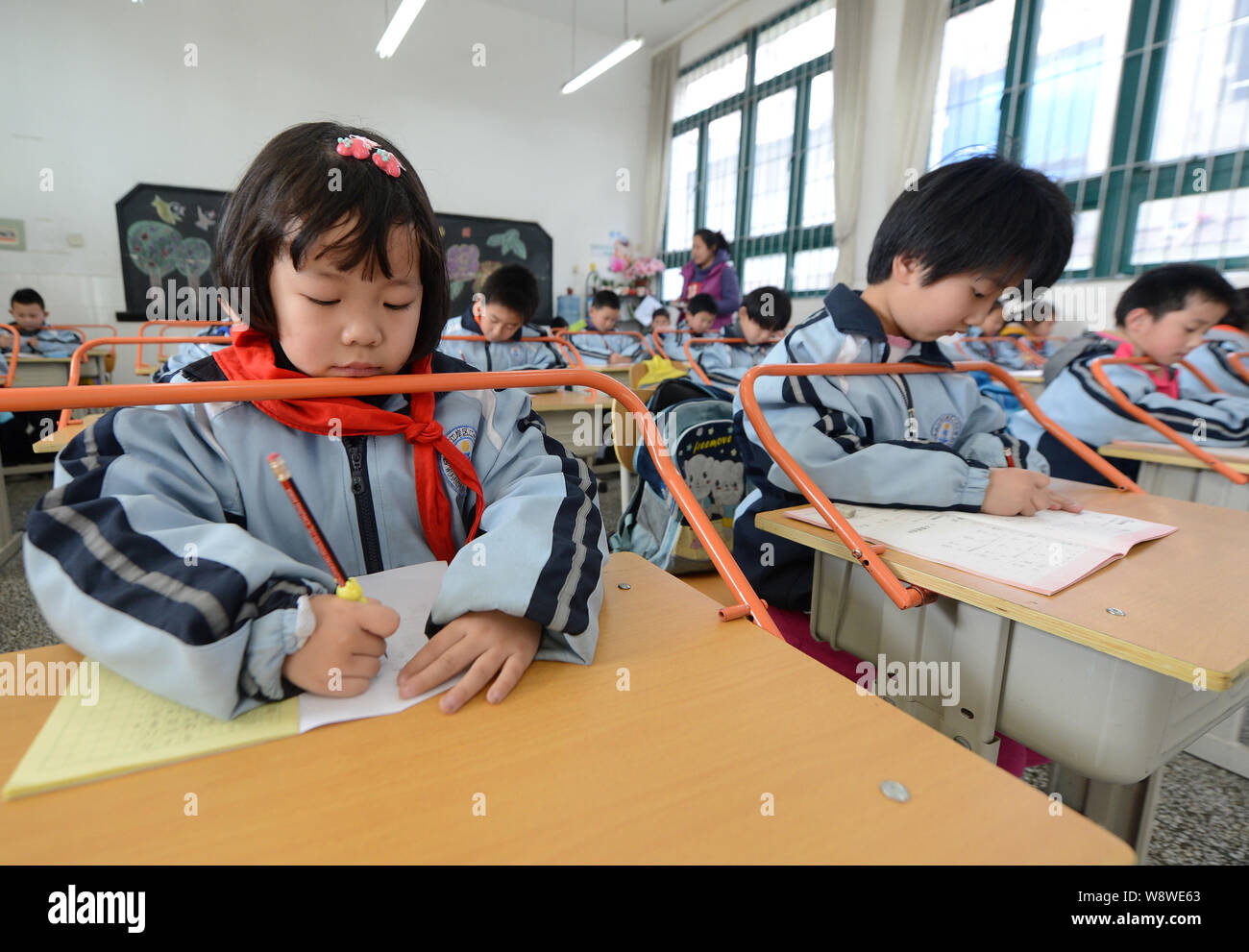 Les écoliers chinois écrire leurs devoirs sur un bureau avec des barres de garder une distance appropriée dans une salle de classe de l'école primaire de Wuhan c Banque D'Images