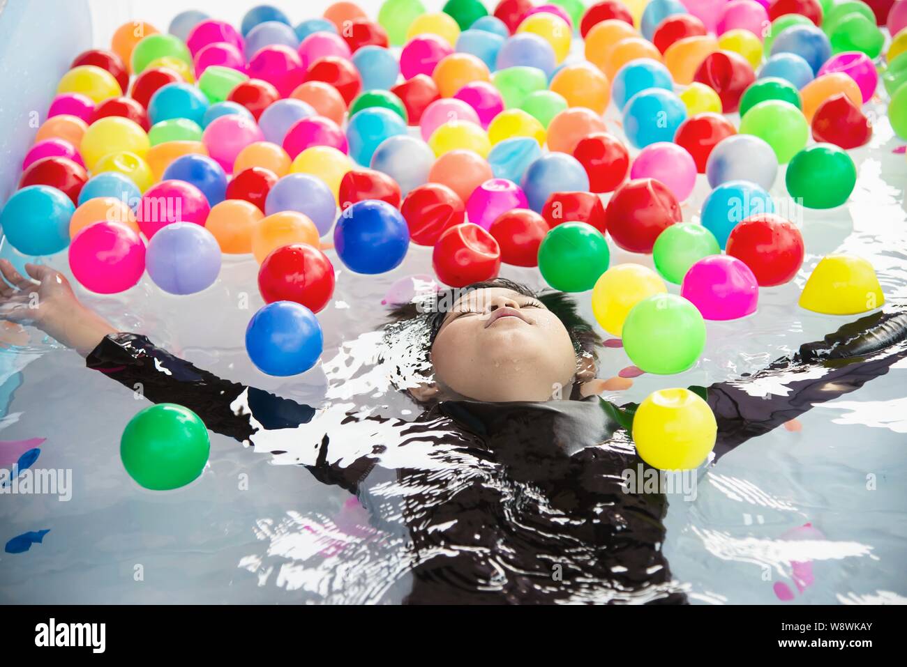 Garçon jouant avec boule colorée en petite piscine toy - happy boy dans l'eau piscine concept jouet Banque D'Images