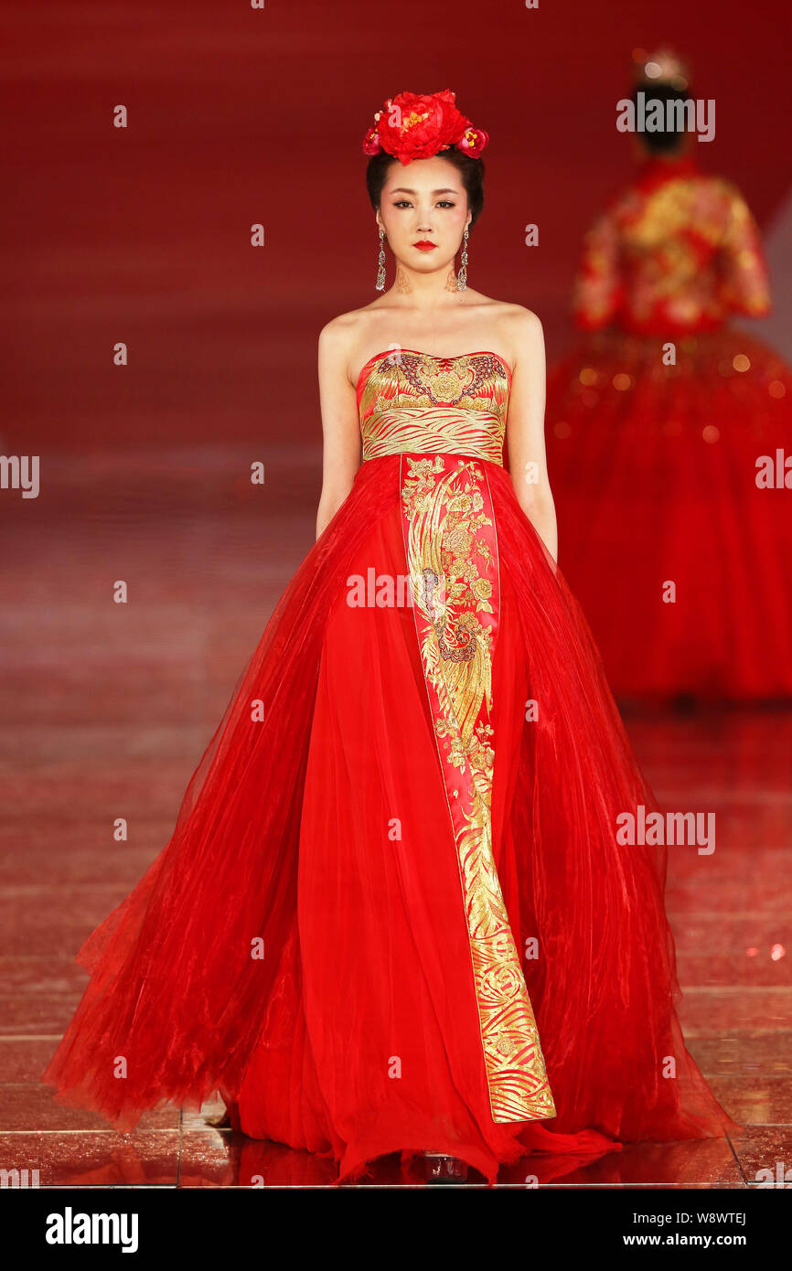 Un modèle affiche une suite nuptiale traditionnelle chinoise robe de mariage de la Rose Studio haute couture par designer Guo Pei lors d'un défilé de mode au cours de la 2014 Sha Banque D'Images