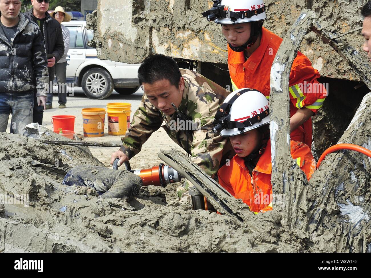 Les membres de l'équipage de sauvetage essayer de sortir une conductrice de la voiture enfouie sous le ciment mouillé pendant un accident de la circulation à Fuzhou City, sud-est, Chine Banque D'Images