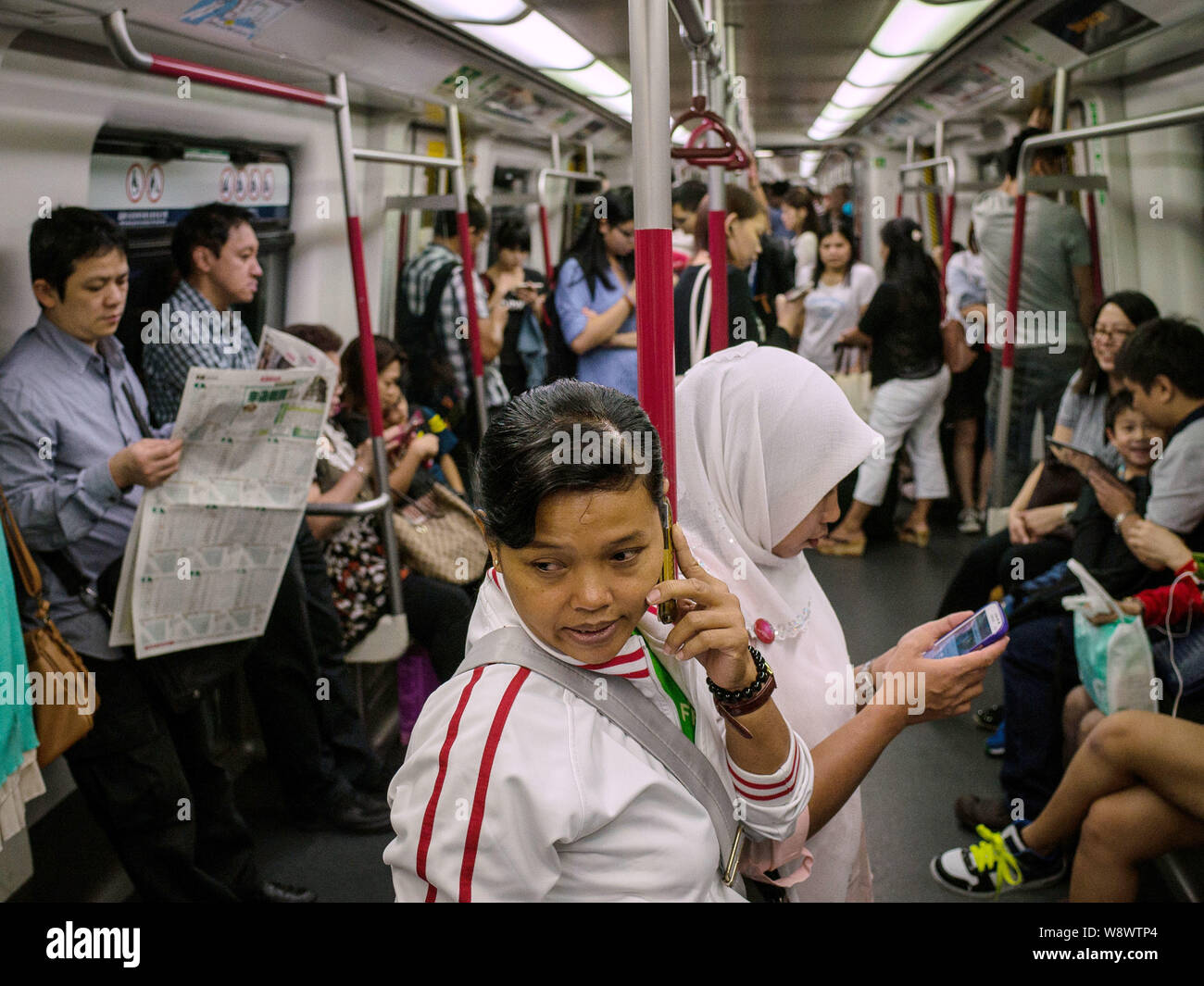 --FILE--deux travailleurs domestiques d'utiliser leurs téléphones mobiles dans une rame de métro de Hong Kong, Chine, 19 octobre 2014. Alors que les manifestations à Hong Kong continue avec Banque D'Images