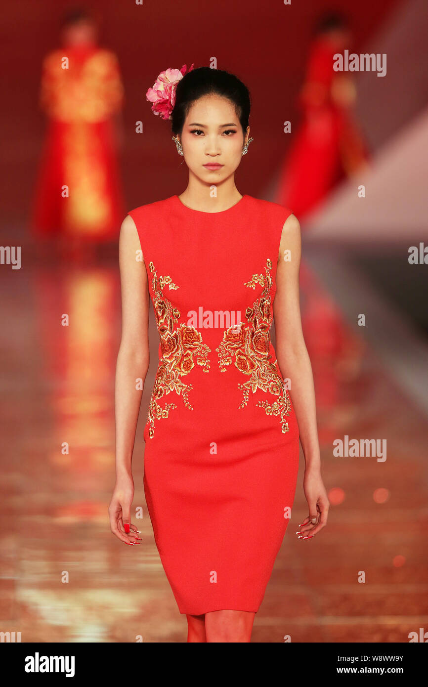 Un modèle affiche une suite nuptiale traditionnelle chinoise robe de mariage de la Rose Studio haute couture par designer Guo Pei lors d'un défilé de mode au cours de la 2014 Sha Banque D'Images