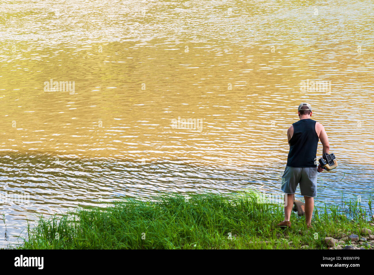Un homme à l'aide d'une garniture à la lutte contre les mauvaises herbes à gazon whacker le long de la rivière Allegheny dans Warren comté en été, Althom, New York, USA Banque D'Images