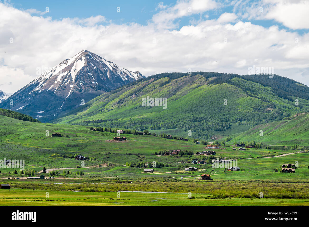 Mount Crested Butte village en été avec des maisons d'hébergement de l'hôtel sur les collines luxuriantes et de couleur verte avec la neige sur la montagne Banque D'Images
