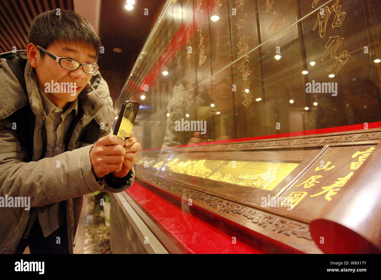 Un visiteur utilise son smartphone pour prendre des photos de la réplique de l'or de l'ancienne peinture chinoise, demeurant dans la montagnes Fuchun, dans le showroom de Banque D'Images