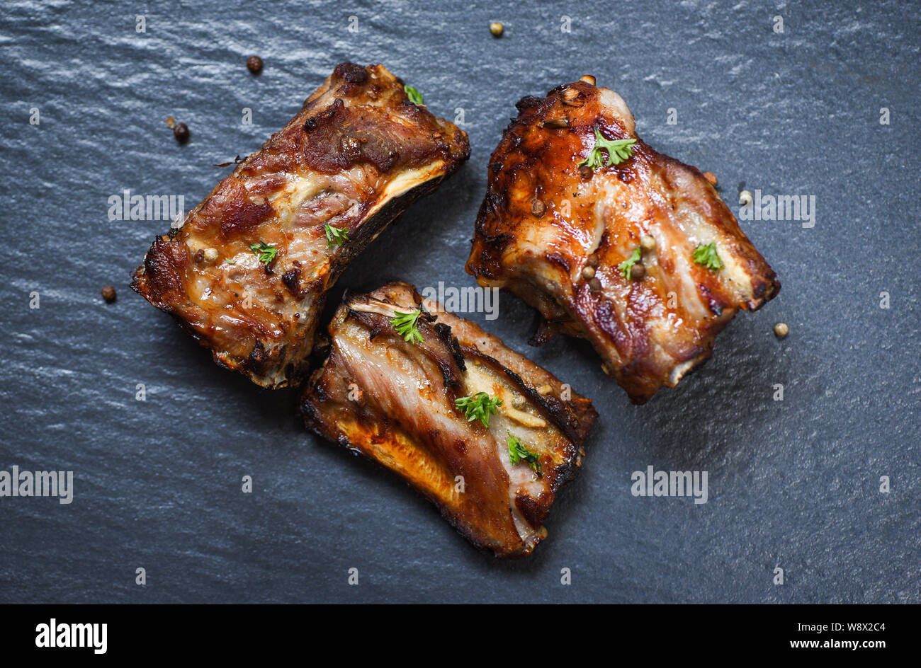 Côtes de porc barbecue avec des herbes et des épices grillées sur barbecue rôti foncé / plaque côtelette de porc tranchés Banque D'Images