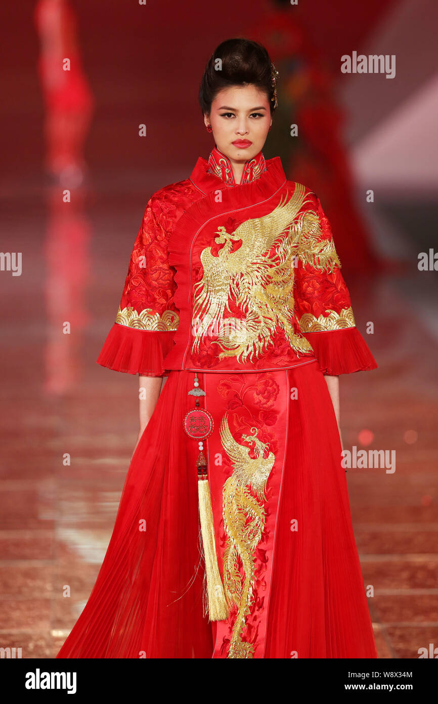 Un modèle affiche une suite nuptiale traditionnelle chinoise robe de mariage de la Rose Studio haute couture par designer Guo Pei lors d'un défilé de mode au cours de la 2014 Sha Banque D'Images