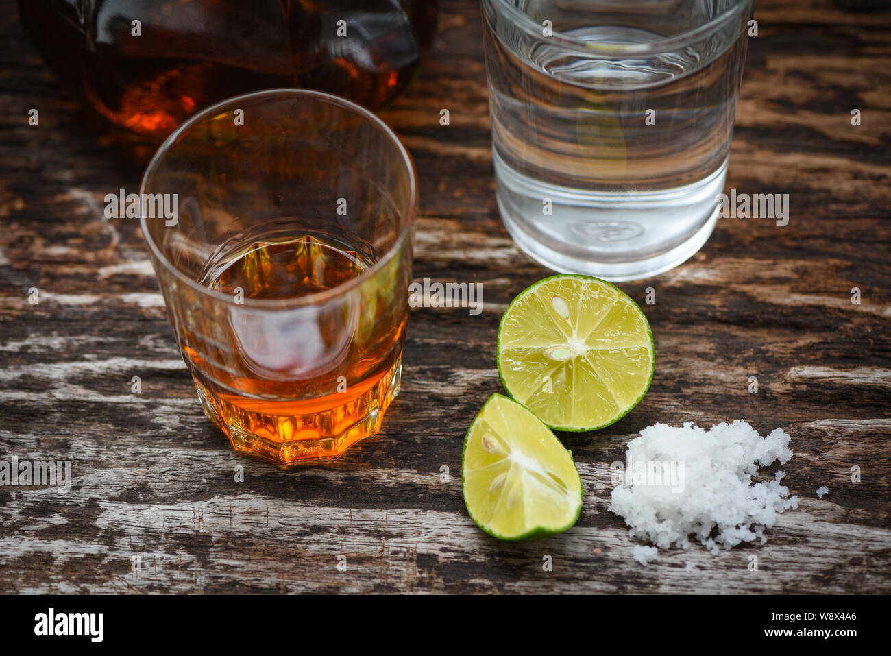 Des boissons alcoolisées et de sel de citron sur fond de bois rustique / le  brandy dans un verre avec de l'alcool et l'eau des bouteilles de rhum  tequila vodka - cognac
