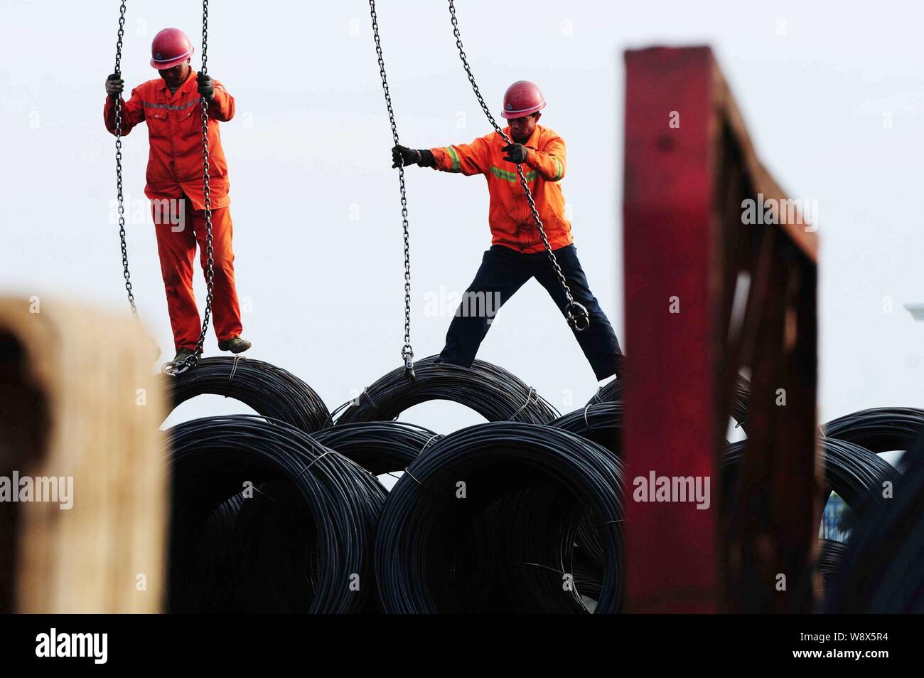--FILE--travailleurs chinois régler les câbles d'avoir des bobines de feuillard, de l'accouplement levé sur un quai du port de Qingdao en Qingdao Shandong, Chine de l'Est Banque D'Images