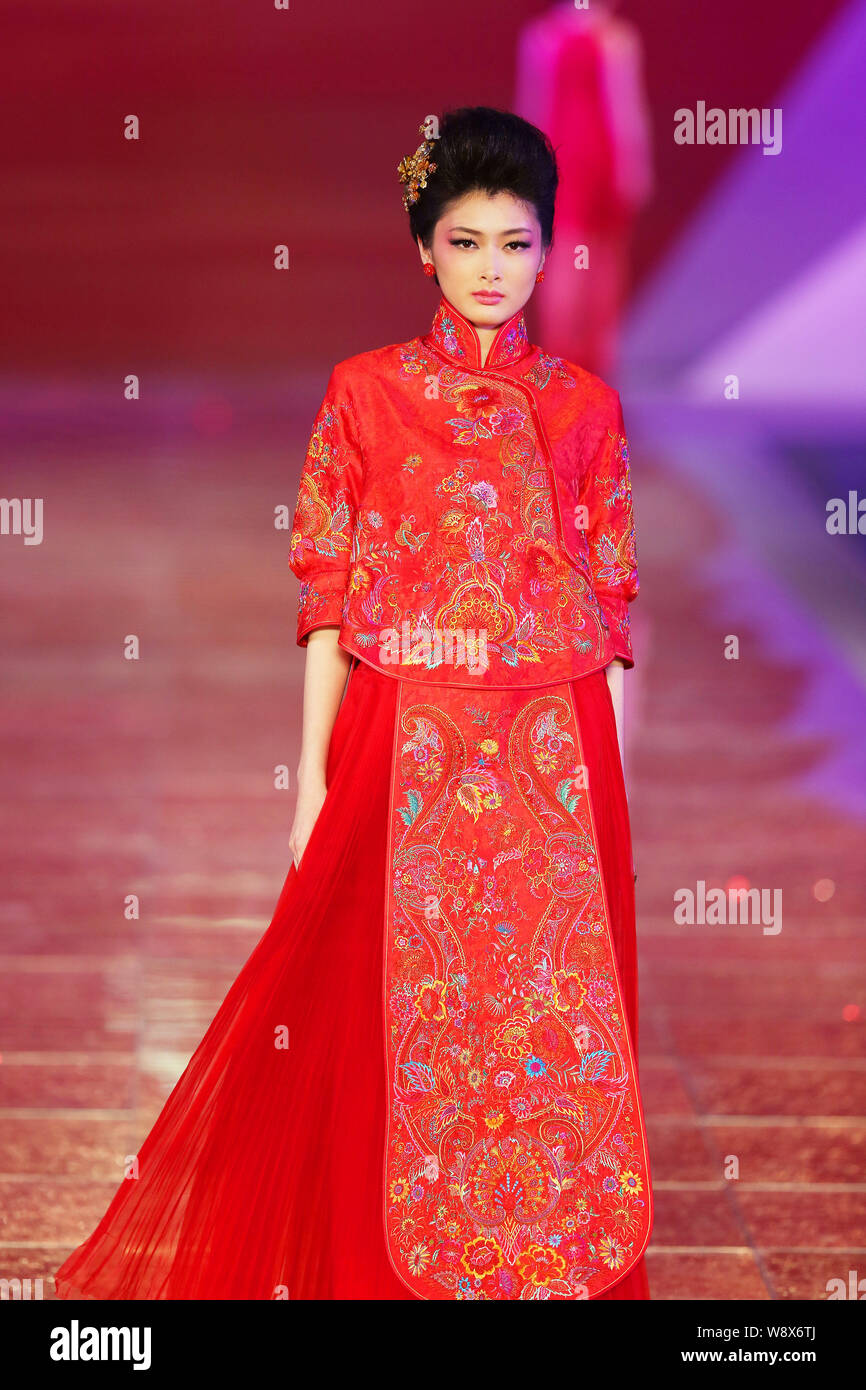 Un modèle affiche une suite nuptiale traditionnelle chinoise robe de mariage de la Rose Studio haute couture par designer Guo Pei lors d'un défilé de mode au cours de la 2014 Sha Banque D'Images