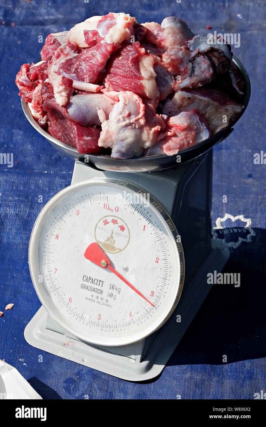 Un tas de viande grasse est pesé sur une balance de poids analogique. Banque D'Images