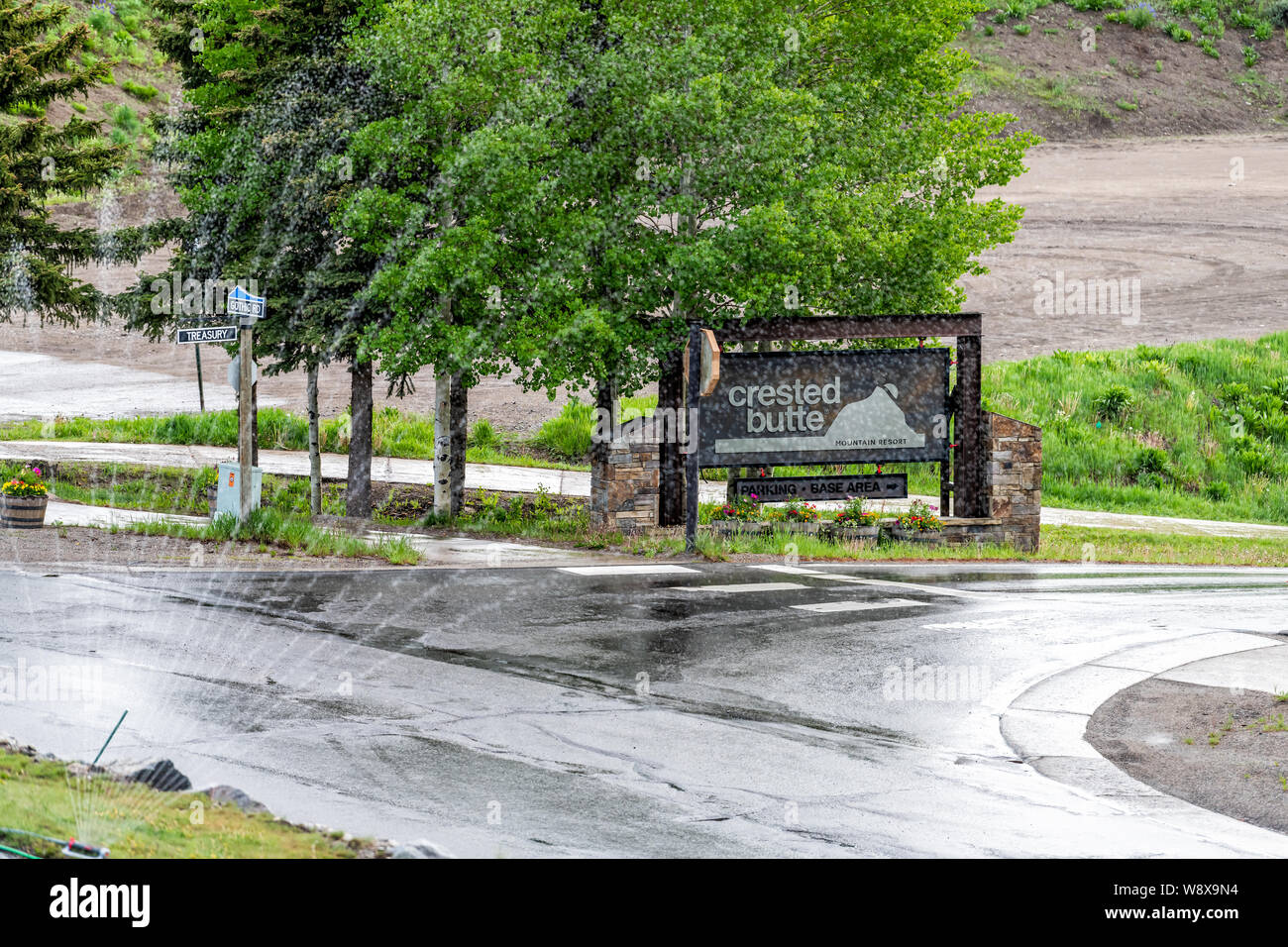 Mount Crested Butte, USA - 22 juin 2019 : Colorado village welcome sign avec aspersion d'eau sur route mouillée et gazon en été Banque D'Images