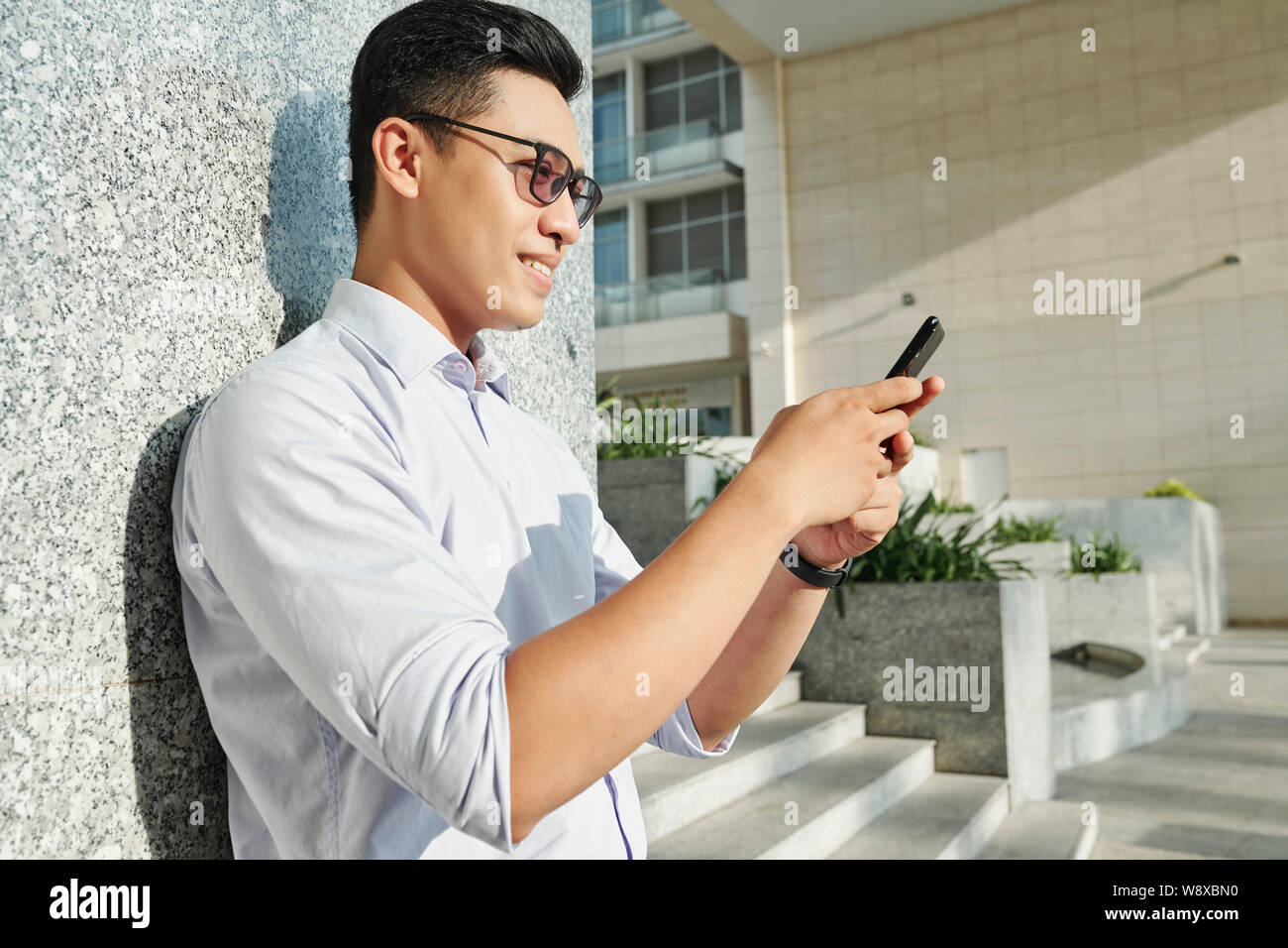 Smiling man reading text message Banque D'Images