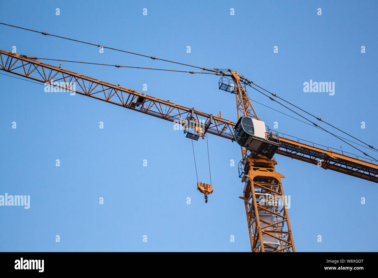 Sur un site de construction, une grande grue est vu du dessous, sa coloration orange Banque D'Images