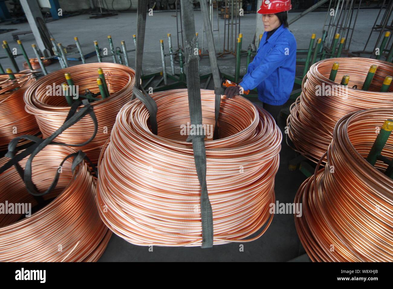 --FILE--Un travailleur chinois mécaniques production de tubes en cuivre enroulé dans une usine dans la ville de Nantong, Chine de l'est de la province de Jiangsu, 16 avril 2011. H Cuivre Banque D'Images