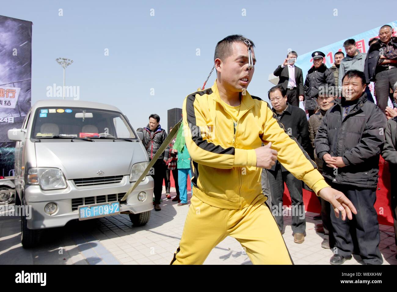 Zhang Cang Yue, un artiste chinois stunt habillé en star de cinéma d'action Hong Kong Bruce Lee, tire une fourgonnette avec une corde attachée à son nez au cours d'une au Banque D'Images