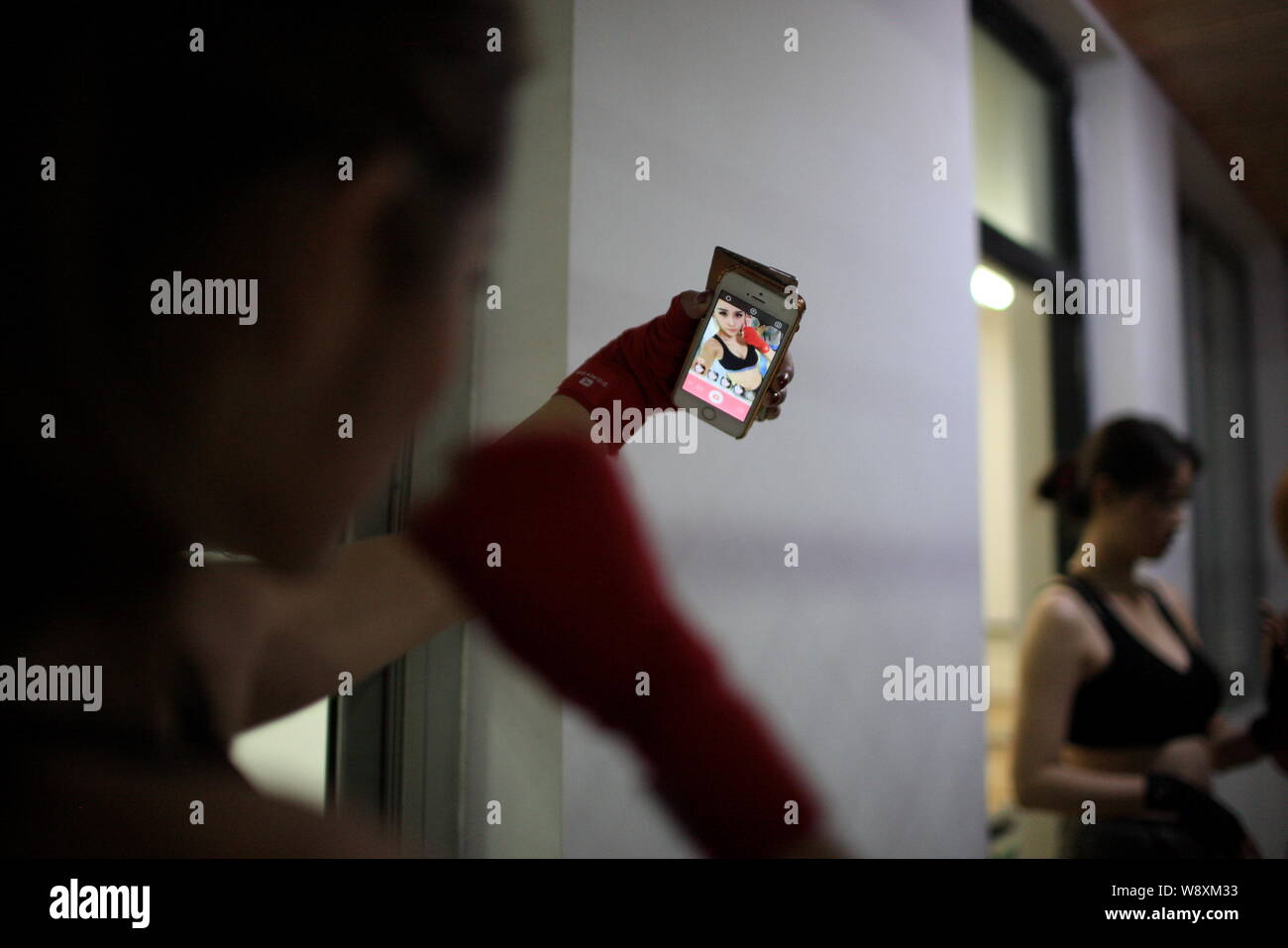Une femme stagiaire utilise son smartphone pour prendre des autoportraits au cours d'un programme de formation de garde du corps au camp d'initialisation de Gengis Security Academy à Beijing, Chin Banque D'Images