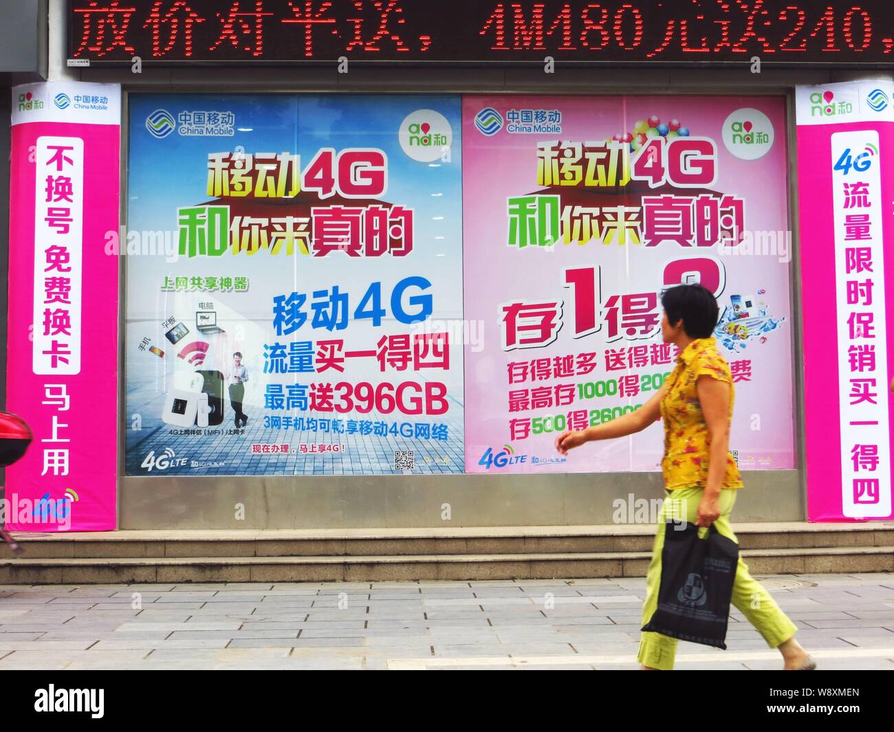 --FILE--un piéton marche dernières publicités pour les réseaux 4G LTE de China Mobile dans la ville de Yichang, province de Hubei, Chine centrale 7 août 2014. Banque D'Images