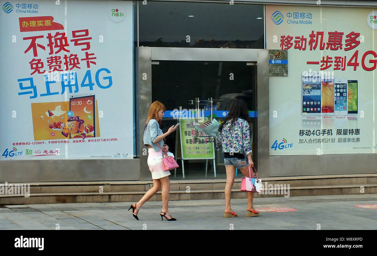 --FILE--piétons passent devant les publicités pour les réseaux 4G LTE de China Mobile dans la ville de Yichang, province de Hubei, Chine centrale 18 mai 2014. Chin Banque D'Images