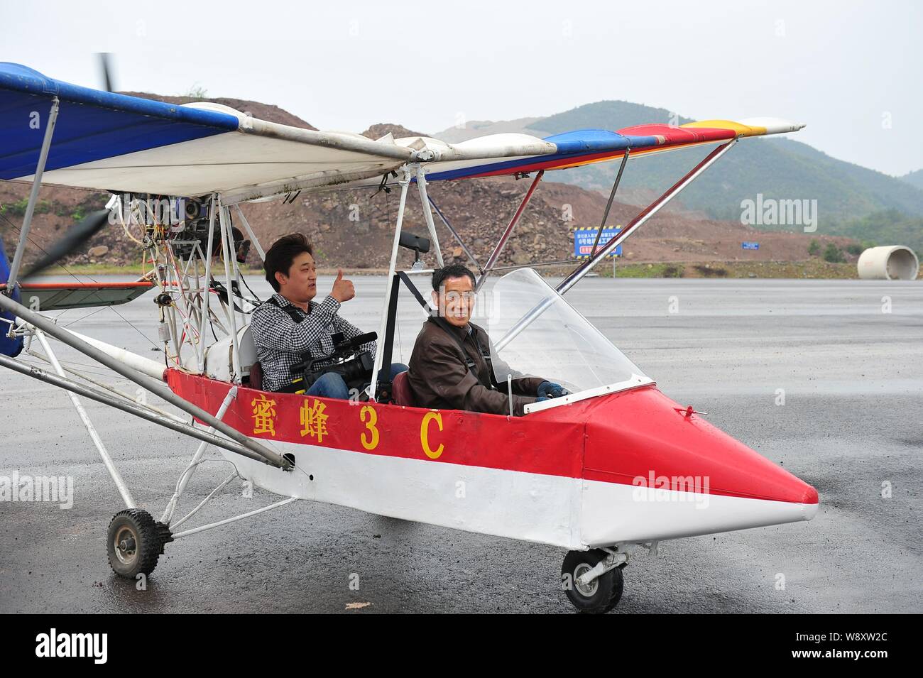 Ancien médecin chinois Jin Shaozhi, droite, commence son abeille fabriqués en Chine-3C super light avion pour transporter un caméraman sur une route en vertu de constructi Banque D'Images