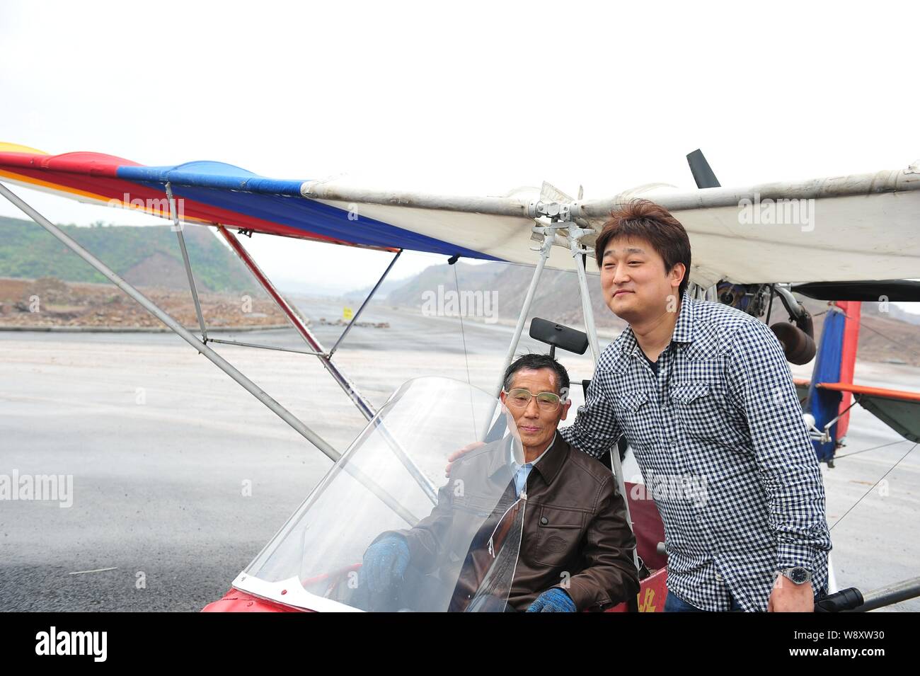 Ancien médecin chinois Jin Shaozhi, gauche, assis dans sa Honeybee fabriqués en Chine-3C super light avion pose avec un caméraman sur une route sous const Banque D'Images