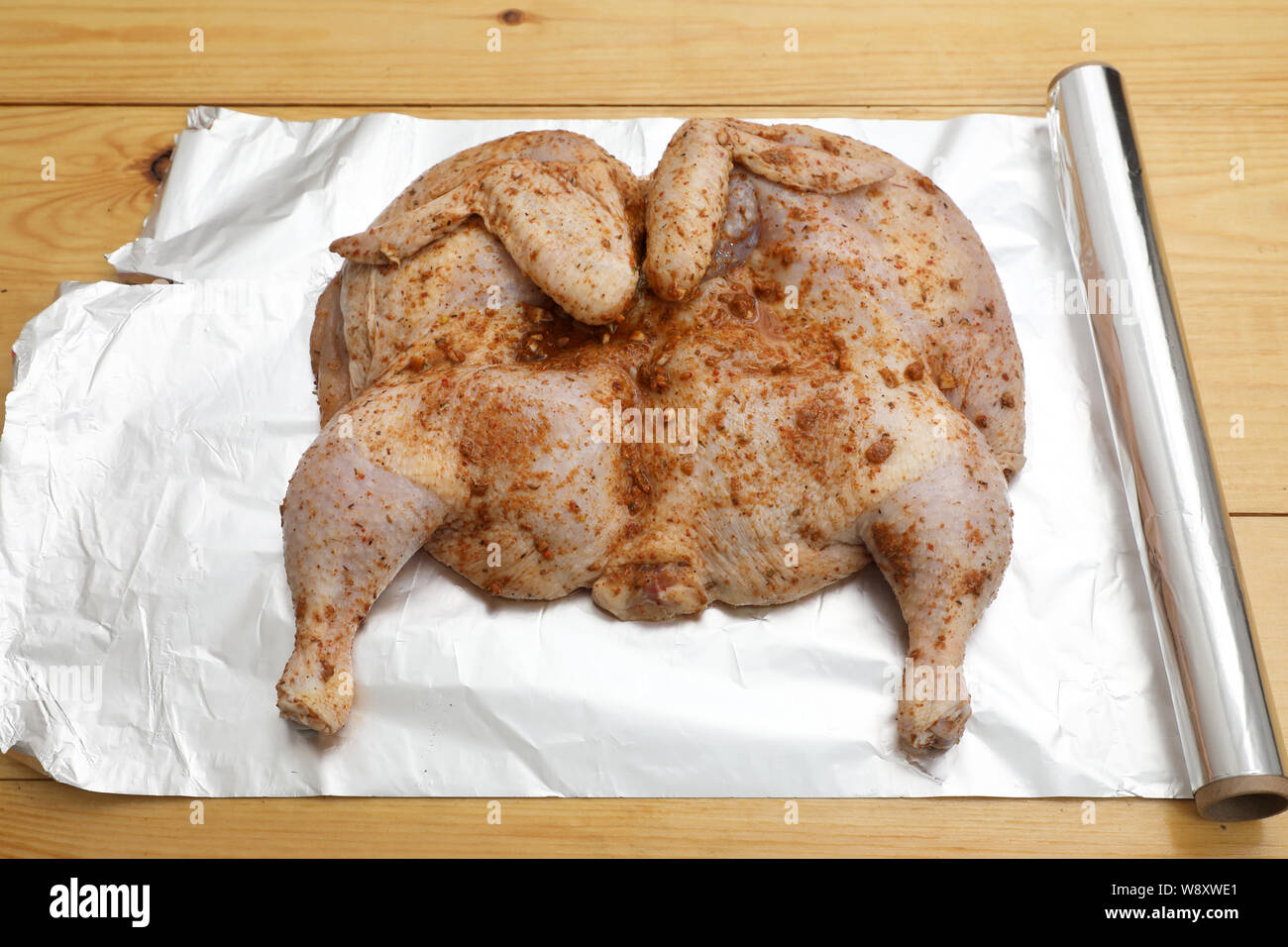 L'ensemble le poulet cru est couvert avec la marinade et l'assaisonnement sur une plaque avant la cuisson . Banque D'Images