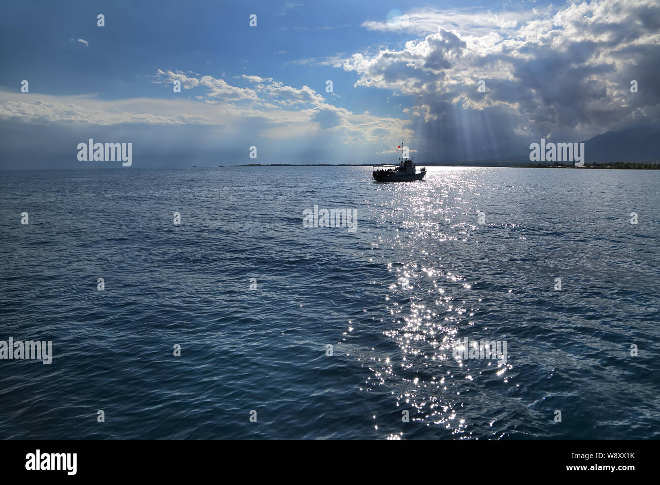 Un petit navire à l'horizon. Les nuages et les rayons du soleil sur la mer. été journée nuageuse sur le lac . L'Issyk-kyl . Kirghizistan Banque D'Images