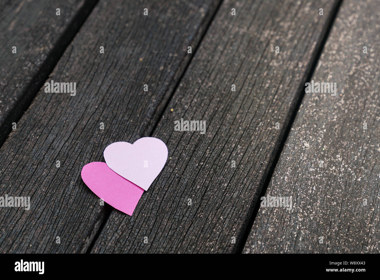 Love concept : deux coeurs en papier sur une carte en bois sombre. Banque D'Images