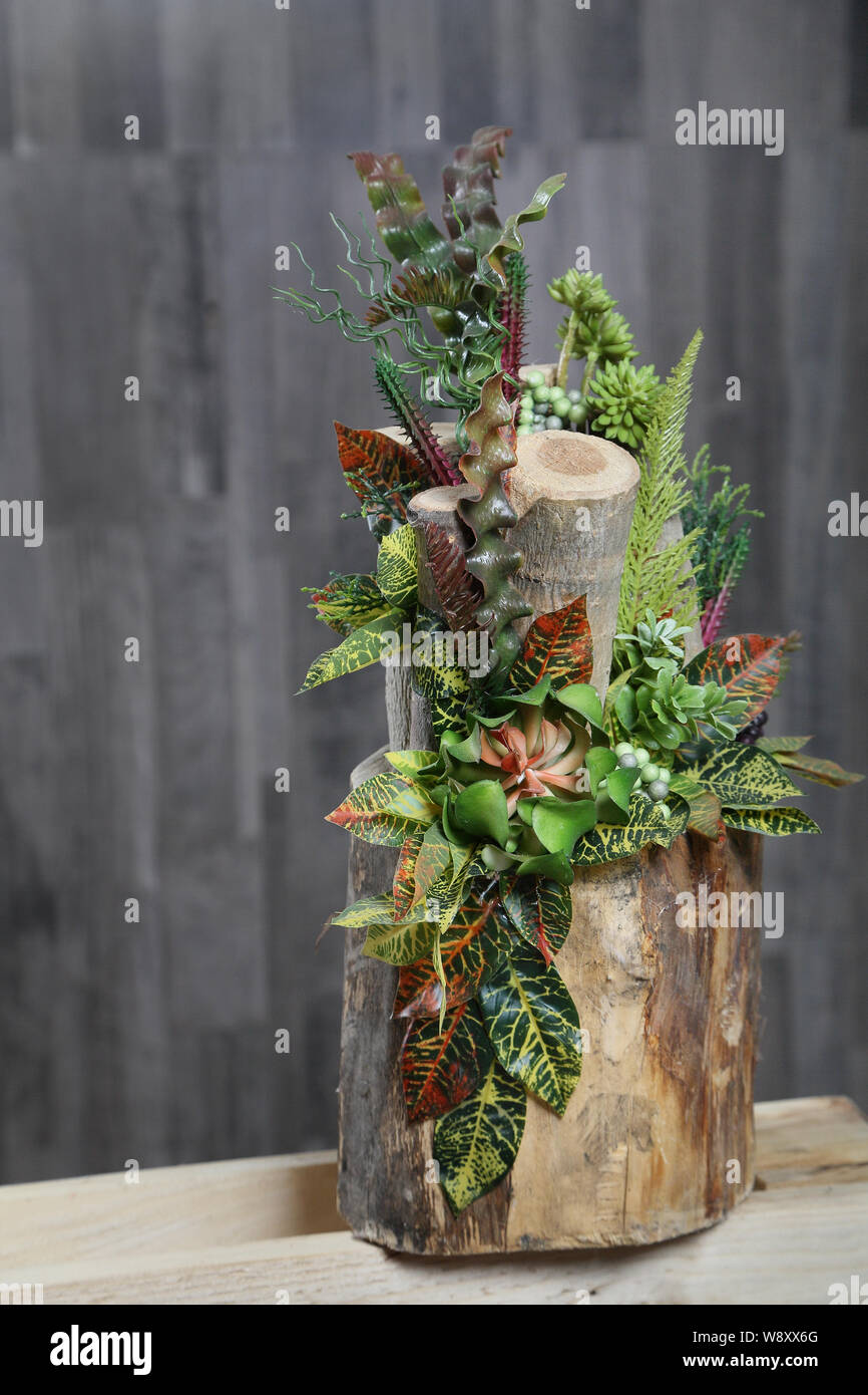 Arrangement floral de fleurs multicolores, des feuilles et des baies en  souche en bois, art floral close-up.Fleurs artificielles Photo Stock - Alamy
