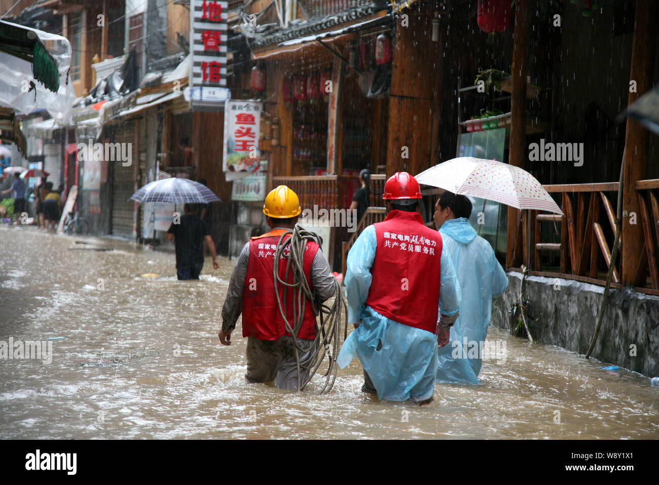 Les travailleurs chinois de State Grid Hunan Branch marcher dans les inondations causées par des pluies torrentielles à Fenghuang county, province de Hunan, Chine centrale, 15 juillet 2014. Banque D'Images