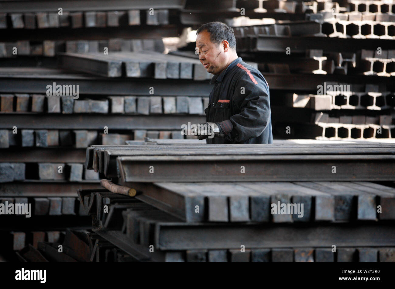 --FILE--Un travailleur chinois examine une pile de produits en acier à une usine de transformation de l'acier dans la ville de Huaibei, east Chines la province de l'Anhui, le 4 avril 2014. Je Banque D'Images