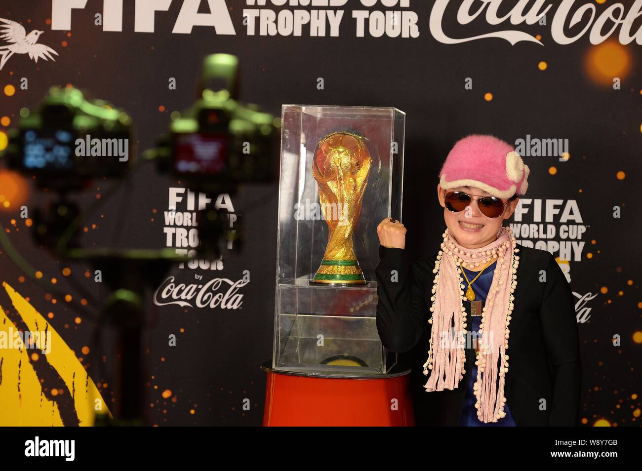 Un visiteur chinois pose avec une réplique de la FIFA Coupe du monde pendant la Coupe du Monde FIFA Trophy Tour à Shanghai, Chine, le 9 avril 2014. Banque D'Images