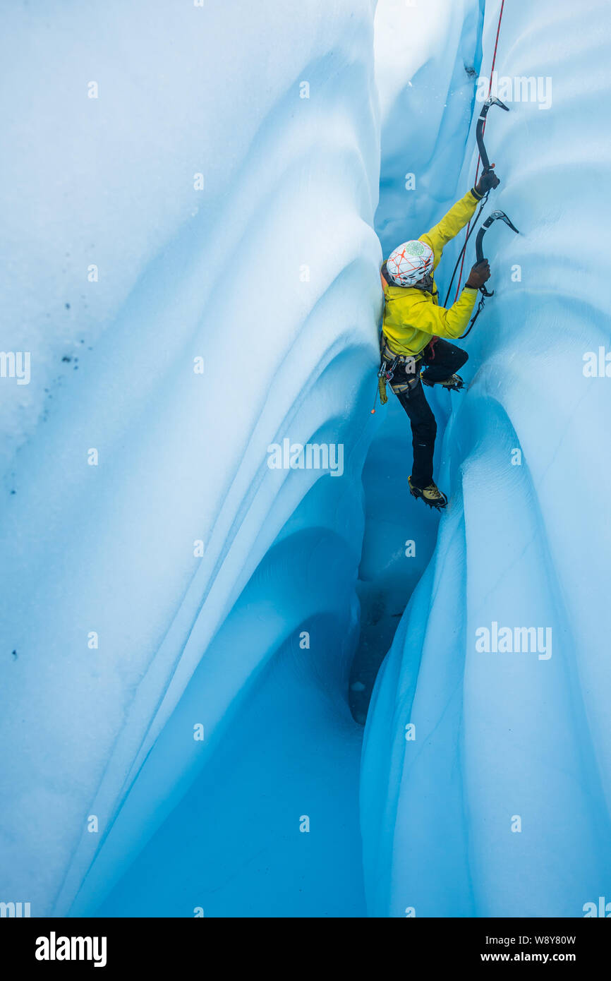Cascade de glace étroit canyon sur le Glacier Matanuska en Alaska. Le grimpeur appuie sur son dos sur le mur en face de l'étroit canyon d'acquérir leverag Banque D'Images